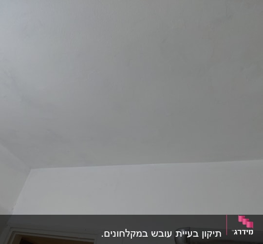 קיר ותקרה צבועים בלבן מעל משקוף דלת ומתקן ממתכת